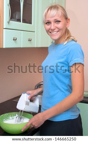 girl makes the food in the kitchen, using a mixer