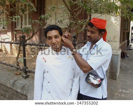 MUMBAI, INDIA - MARCH 13: Unidentified men, an ear cleaner at work on a hotel employee on a street corner on March 13, 2010  in Mumbai (Bombay), India.  Hygiene is of great importance in India.
