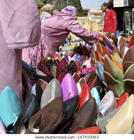 MEKNES, MOROCCO - APRIL 6: Unidentified women buy slippers, babouches, from a stall holder in the souk on April 6, 2011. These slippers have become popular in Europe