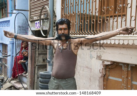 BIKANER, RAJASTHAN, INDIA - MARCH 27: Unidentified man unfurls and shows off his very long moustache on March 27, 2012. Growing long moustaches is popular in Rajasthan, competitions are often held.
