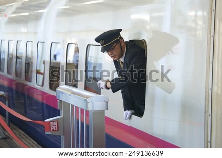 TOKYO, JAPAN - NOV 10: Shinkansen (Bullet Train) conductor checks time for prompt departure at Tokyo station, on November 10, 2014, in Tokyo, Japan. Shinkansen trains are known for being punctual.