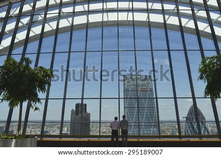 LONDON, UK - JULY 9, 2015: View from the SkyGarden at 20 Fenchurch Street.  2 men look out towards The Leadenhall Building, The Gherkin (30 St Mary Axe) and Tower 42 in London UK.
