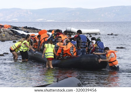 LESVOS, GREECE SEPTEMBER 24, 2015: Refugees arriving in Greece by boat from Turkey.  These Syrian refugees are helped, by Norwegian volunteers, to land their boat near Molyvos, Lesvos (Mytilene).