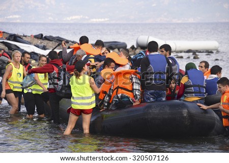 LESVOS, GREECE   SEPTEMBER 24, 2015: Refugees arriving in Greece by boat from Turkey.  These Syrian refugees are helped, by Norwegian volunteers, to land their boat near Molyvos, Lesvos (Mytilene).