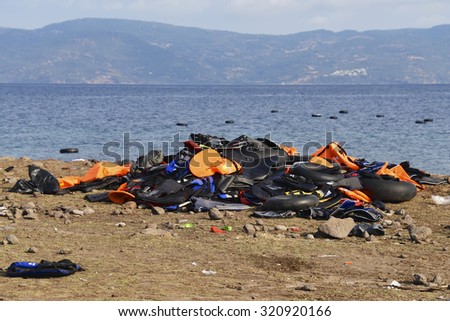 LESVOS, GREECE SEPTEMBER 24, 2015: Lifejackets discarded on a beach near Molyvos & rubber rings in the sea. Lesvos has been a hot spot for migrants & refugees arriving in boats, Turkey in background.