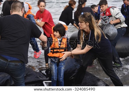 LESVOS, GREECE - SEPTEMBER 29, 2015: Syrian refugee child given help ashore, from volunteers, after crossing to Lesbos, Greece in an inflatable raft from Turkey.
