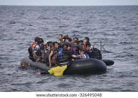 LESVOS, GREECE - SEPTEMBER 29, 2015: Refugees arriving in Greece by boat from Turkey. Volunteer lifeguards swam out to assist and guide the boat in when the motor failed.
