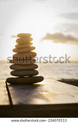 Stack of pebbles on a table at the beach at sunset . Concept of balance and harmony.