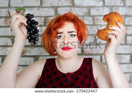 sad Red-haired girl in pin-up style on diet with food