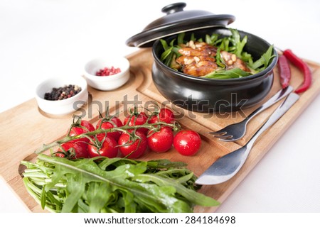 Salad with eel, arugula, cherry tomatoes and pine nuts on wooden board isolated on white background