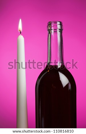 Candle and wine bottle in a pink romantic light