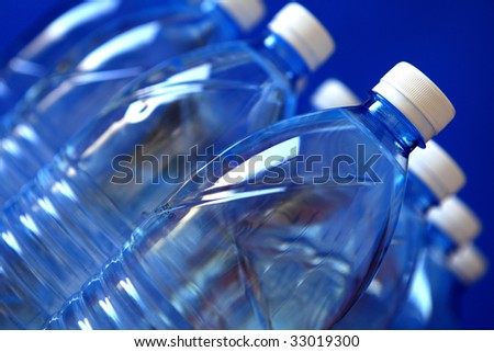 Mineral water bottles isolated on blue background, close up