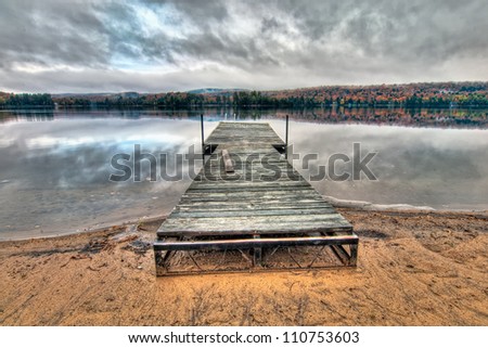 Dock in the middle of a lake with reflection of dramatic clouds.