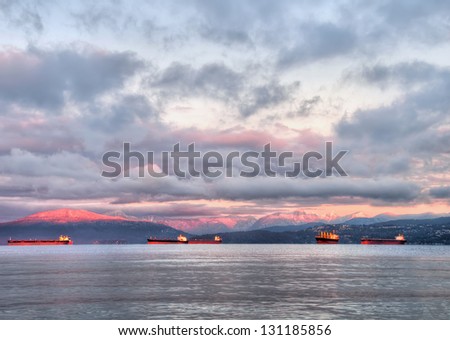 Pink mountains at sunrise with tanker boats in foreground.