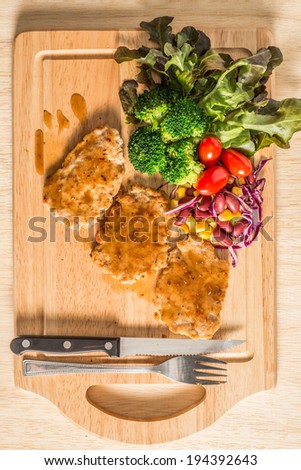Pork cube steak topped with pepper sauce and creamy salad on wood plate