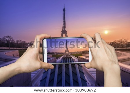 Girl taking pictures on mobile smart phone in eiffel tower, Paris, France