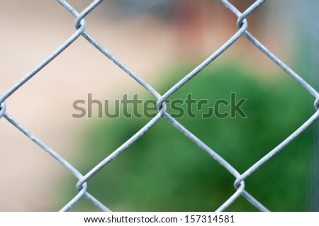 Wire Mesh Fence Close-Up on Green Background.