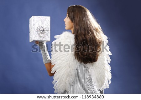 Beautiful woman from rear with angel wings holds a silver gift