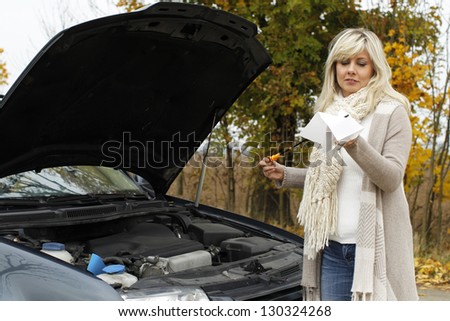Woman checks oil level - car breakdown