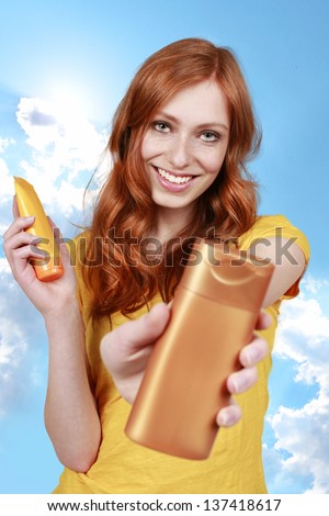 Red haired woman with sun lotion