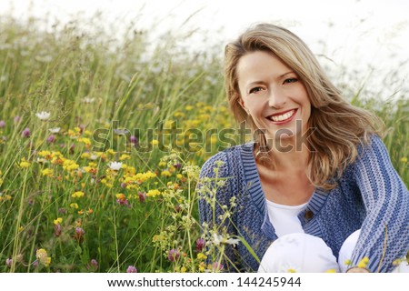 Happy Woman With A Flower Relaxes In The Grass With A Flower