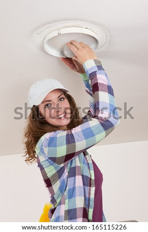 Woman tries to change a bulb on the ceiling