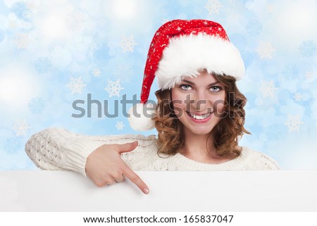 Happy woman with santa hat points to an empty board