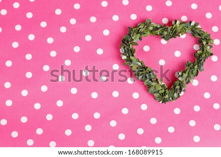 Green floral heart in front of pink white dotted background