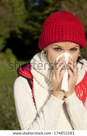 Young woman is blowing her nose outdoor