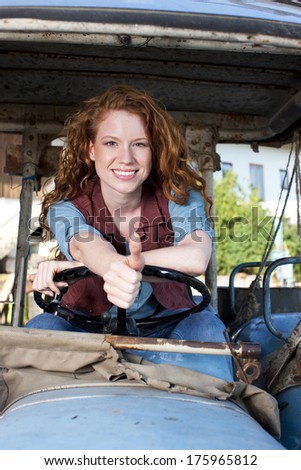Smiling woman on a tractor with thumb up
