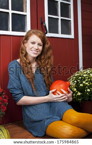 Young woman with pumpkin in front of a summer house outdoor