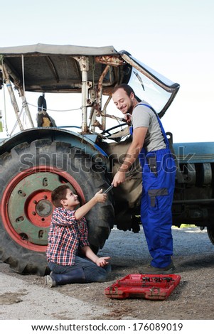 Father and son repairing a tractor on a farm