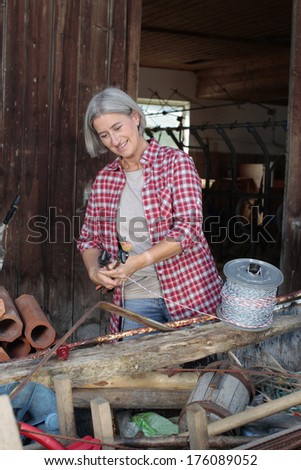 Matured farm woman at work in front of a barn