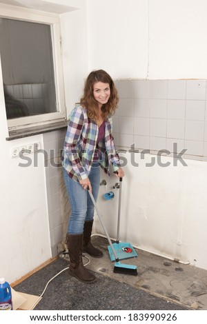 Woman sweeps up dust from the floor
