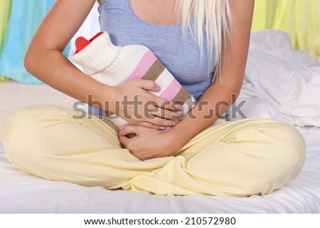 Woman with hot bottle and stomach pain