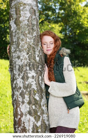Young woman leaning against a birch tree