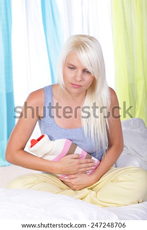Woman with hot bottle and stomach pain in bed