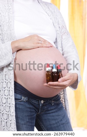 Pregnant woman with little bottles of homeopathic medicine in front of her belly