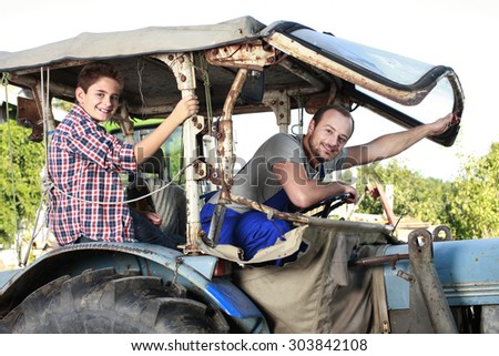 Father and son driving on a tractor on a farm
