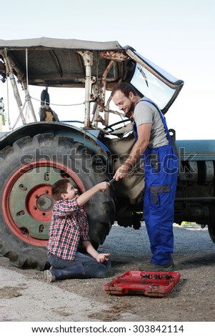 Father and son repairing a tractor on a farm