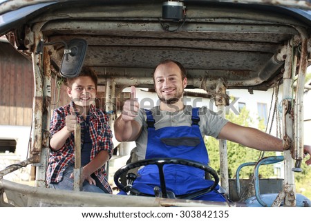 Father and son driving on a tractor on a farm