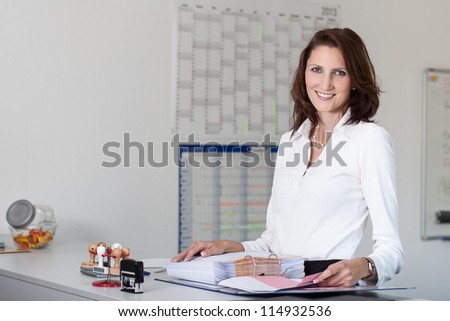 Young, beautiful businesswoman handles files in office