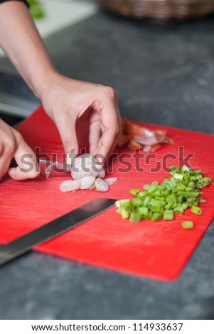 Woman cuts onion on a kitchen bench in the kitchen