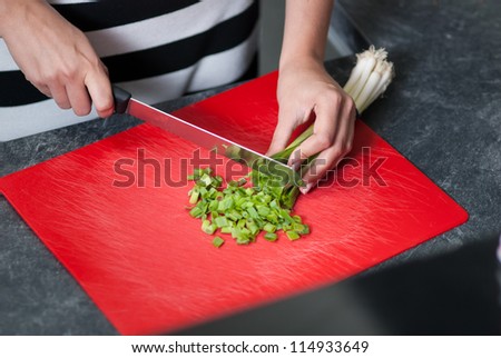 Woman cuts leek on a kitchen bench in the kitchen