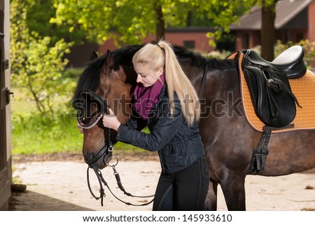 Girl bridles her brown horse (New-Forest-Pony)
