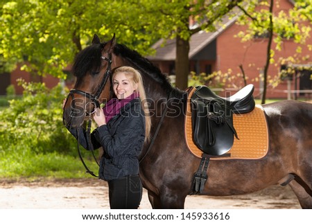 Girl is holding her brown pony (New-Forest-Pony) at the bridle