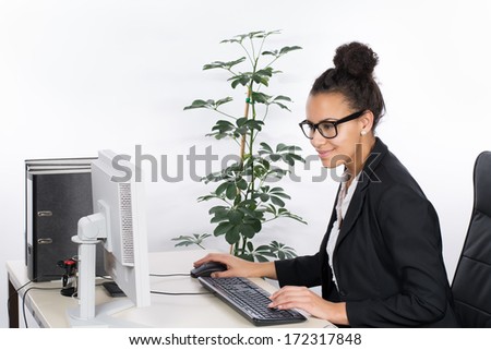 Young, beautiful business woman sits at the desk in the office and works at the pc