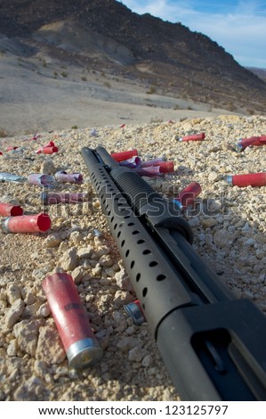 pump-action shotgun on ground surrounded by empty cartridges
