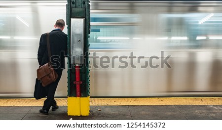 Young Business man at subway station stop waiting for the train to stop, blurry motion blur moving train background