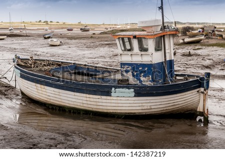 Old wooden fishing boat on mud flats at Brancaster Norfolk England